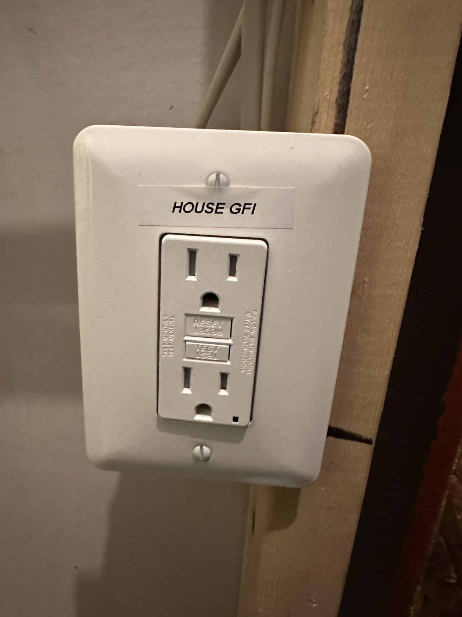 A GFCI receptacle labeled HOUSE GFI, installed beside the panel in a Fairfax basement