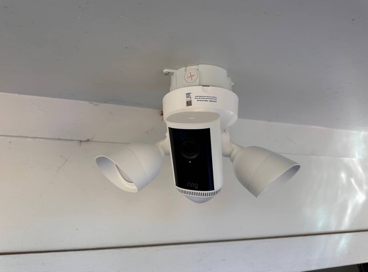 Ring floodlight camera with two flood lights mounted on a soffit — wired security camera installation