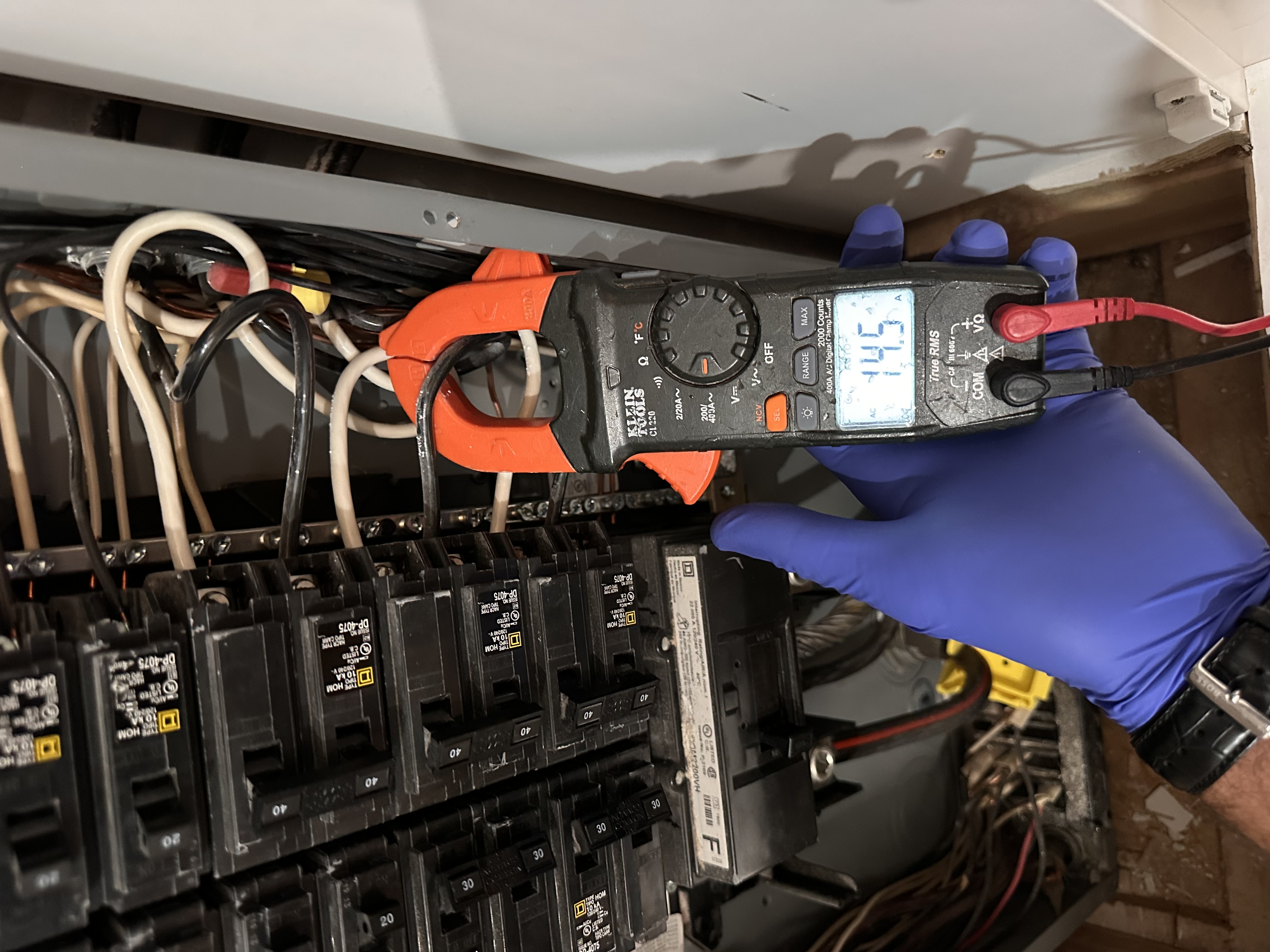 Clamp meter reading a live electrical panel during troubleshooting — EV-Electric Services, Fairfax VA