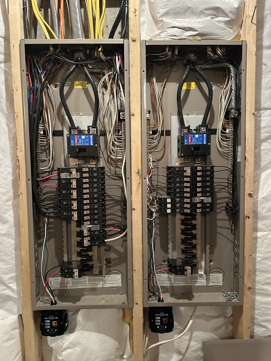 Two electrical panels side by side, each with a surge protector unit mounted underneath